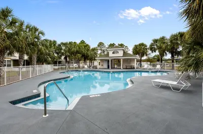 a large swimming pool with a bench and palm trees at The Sandbox by Book That Condo in Panama City Beach