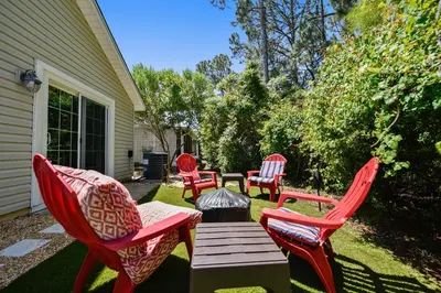a group of red chairs and a table on a yard at The Sandbox by Book That Condo in Panama City Beach