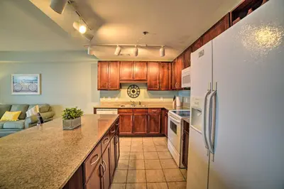 a kitchen with wooden cabinets and a white refrigerator at 18th-Floor PCB Resort Condo with Amazing Gulf View! in Panama City Beach