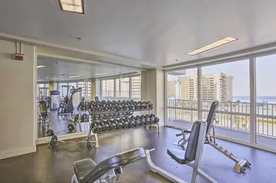 a gym with rows of exercise equipment and large windows at 18th-Floor PCB Resort Condo with Amazing Gulf View! in Panama City Beach