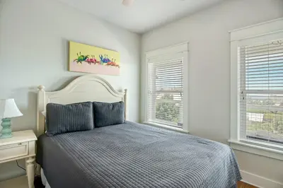 a bedroom with a bed and two windows at Sea It All in Santa Rosa Beach