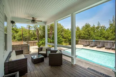 a screened in porch with a pool with chairs and a couch at Sea It All in Santa Rosa Beach