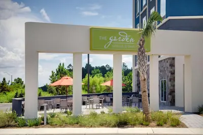 a restaurant with tables and chairs and a palm tree at Hilton Garden Inn Panama City Airport, Fl in Panama City