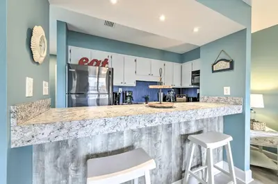 a kitchen with a large counter with two stools at Panama City Condo with Balcony and Pool, Walk to Beach in Panama City Beach