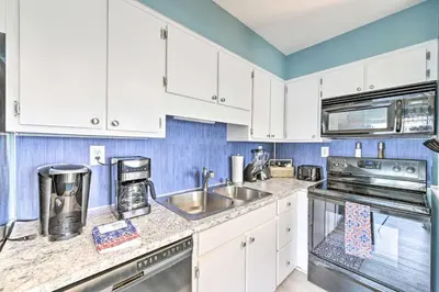 a kitchen with white cabinets and a sink at Panama City Condo with Balcony and Pool, Walk to Beach in Panama City Beach