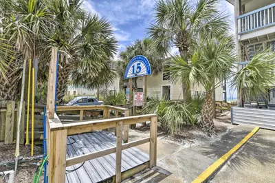 a sign in front of a building with palm trees at Panama City Condo with Balcony and Pool, Walk to Beach in Panama City Beach