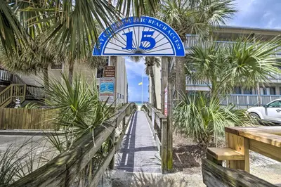 a clock on the side of a building with palm trees at Panama City Condo with Balcony and Pool, Walk to Beach in Panama City Beach