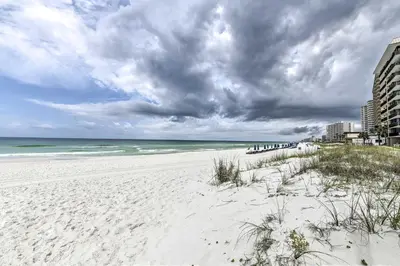 a white beach with the ocean and buildings at Panama City Condo with Balcony and Pool, Walk to Beach in Panama City Beach