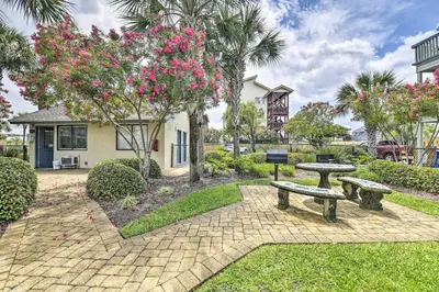 a park with two picnic tables and a tree with pink flowers at Panama City Condo with Balcony and Pool, Walk to Beach in Panama City Beach