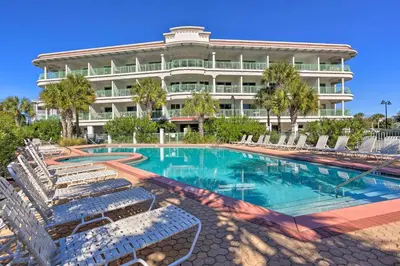 a swimming pool with chairs and a building at Ocean View Condo Btwn Rosemary and Alys Beach! in Rosemary Beach