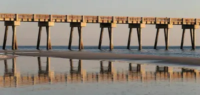 a pier on the beach with its reflection in the water at Nautical Watch Gulf Side Villas B-13 in Panama City Beach