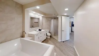 a white bathroom with a tub and a toilet at Dunes of Panama E-1006 in Panama City Beach