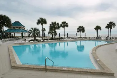 a large swimming pool with palm trees and the ocean at Dunes of Panama E-1006 in Panama City Beach