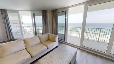 a living room with a couch and views of the ocean at Dunes of Panama E-1006 in Panama City Beach