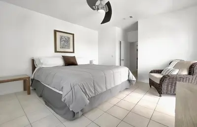 a white bedroom with a bed and a chair at Ocean Air Upper West Private Beach Unit on 30A in Santa Rosa Beach