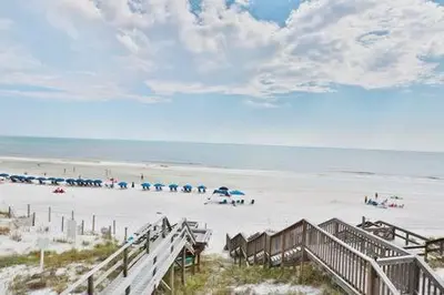 a beach with umbrellas and people on the sand at Ocean Air Upper East Private Beach unit on 30A in Santa Rosa Beach