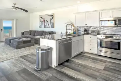 a kitchen and living room with white cabinets and a couch at Ocean Air Upper East Private Beach unit on 30A in Santa Rosa Beach
