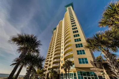 a tall building with palm trees in front of it at Aqua Resort 1705 in Panama City Beach