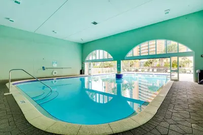a large swimming pool in a building with a large window at Beachfront PCB Condo with Ocean View and Pool Access! in Panama City Beach