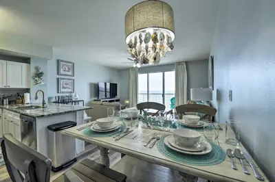 a kitchen and dining room with a table with a chandelier at Beachfront PCB Condo with Ocean View and Pool Access! in Panama City Beach