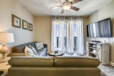 a living room with a couch and a tv at Grand Panama Beach Resort #908-1 by Book That Condo in Panama City Beach