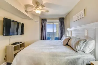 a bedroom with a bed with a television and a window at Grand Panama Beach Resort #908-1 by Book That Condo in Panama City Beach