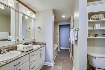 a white bathroom with two sinks and a toilet at Grand Panama Beach Resort #908-1 by Book That Condo in Panama City Beach