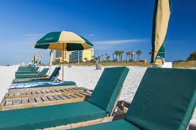 a row of lounge chairs and an umbrella on the beach at Grand Panama Beach Resort #908-1 by Book That Condo in Panama City Beach