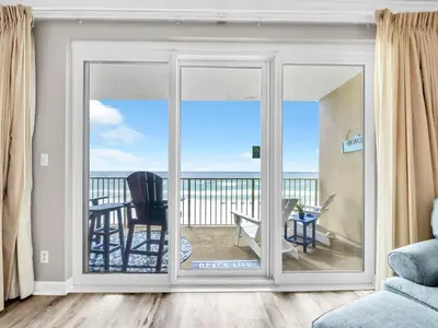 a room with a sliding glass door with a view of the ocean at Grandview East 302 - Sandscape in Panama City Beach