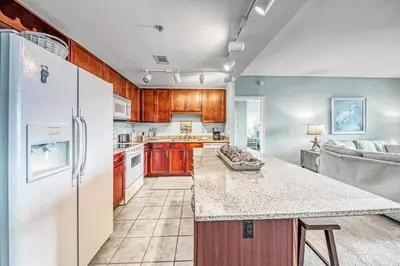 a kitchen with wooden cabinets and a white refrigerator at On the 3-d Floor, Laketown 324 - Large 2 BD , Great Views and Amenities in Panama City Beach