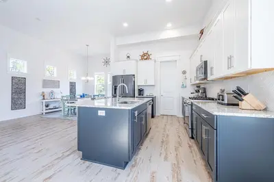 a large kitchen with white cabinets and blue appliances at Vitamin Sea in Inlet Beach