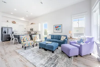 a living room with purple furniture and a kitchen at Vitamin Sea in Inlet Beach