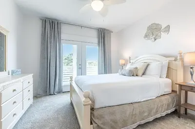 a white bedroom with a bed and a window at Vitamin Sea in Inlet Beach