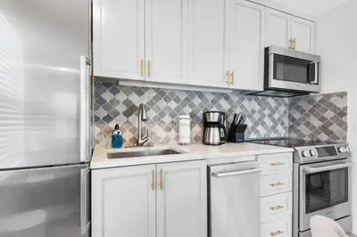 a kitchen with white cabinets and a stainless steel refrigerator at Inlet Sands 206- Inlet Dreams in Panama City Beach