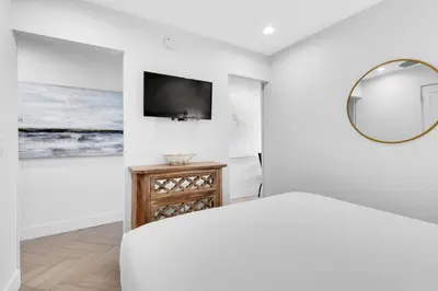a white bedroom with a bed and a mirror at Inlet Sands 206- Inlet Dreams in Panama City Beach