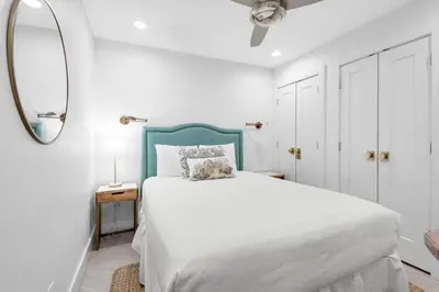 a bedroom with a bed with a blue headboard and a mirror at Inlet Sands 206- Inlet Dreams in Panama City Beach