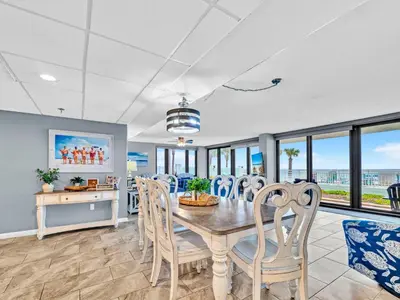 a dining room with a table and chairs and windows at Watercrest 103 in Panama City Beach