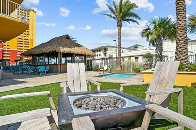 a fire pit in a park with two wooden chairs at Calypso Resort Tower 3 in Panama City Beach