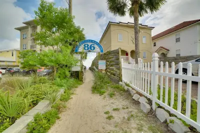 a white fence next to a house with a sign at West End Home with Yard Less Than 1 Mi to Beach Access! in Panama City Beach