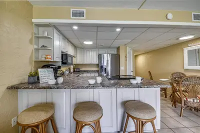 a kitchen with a counter with bar stools at Sea Hag by Book That Condo in Panama City Beach