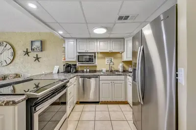 a kitchen with white cabinets and a stainless steel refrigerator at Sea Hag by Book That Condo in Panama City Beach