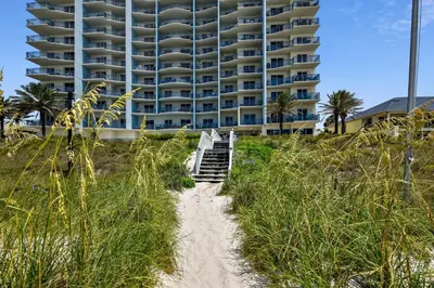 a path leading to a beach with a tall building at Sterling Breeze #1702 by Book That Condo in Panama City Beach