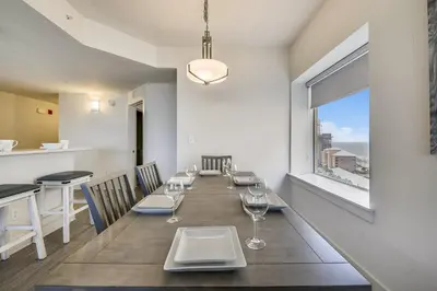 a dining room with a long table with chairs and a window at Calypso Resort and Towers #1101-3 by Book That Condo in Panama City Beach