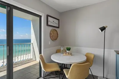 a dining room with a table and a balcony with the ocean at The Summit 919 in Panama City Beach
