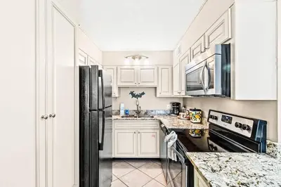 a kitchen with white cabinets and a black refrigerator at The Summit 820 in Panama City Beach