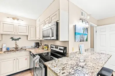 a kitchen with white cabinets and granite counter tops at The Summit 820 in Panama City Beach