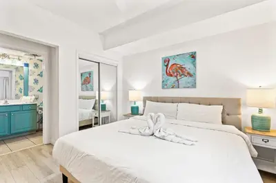 a white bedroom with a large white bed and a bathroom at Seychelles 1006 in Panama City Beach