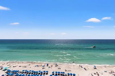 a group of people on a beach with umbrellas and the ocean at Seychelles 1006 in Panama City Beach