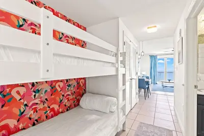 a bedroom with two bunk beds and a dining room at Seychelles 1006 in Panama City Beach