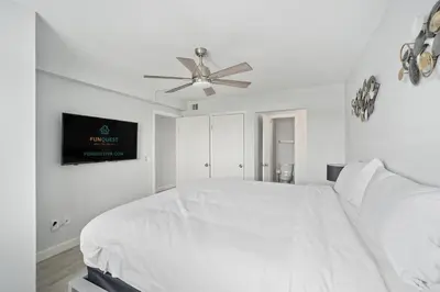 a white bedroom with a bed and a ceiling fan at The Summit 626 in Panama City Beach